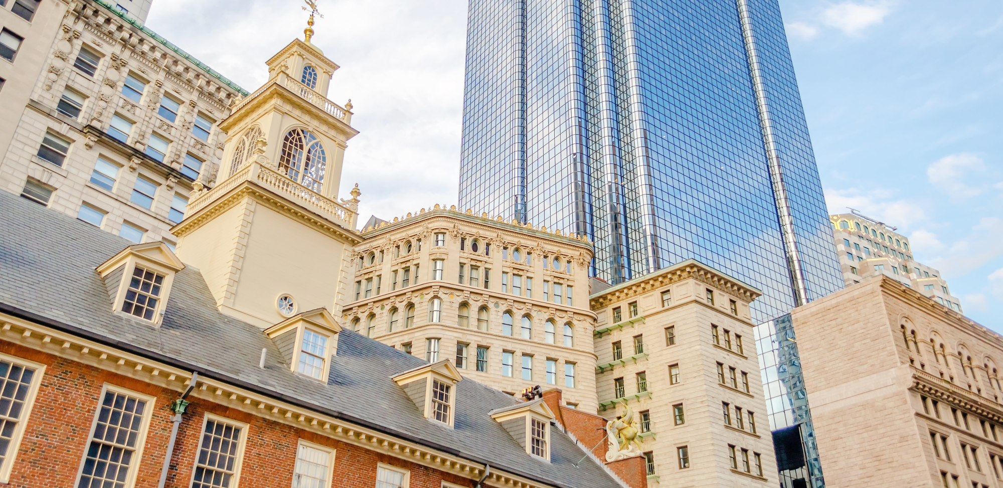 A photo of the old Boston state house with modern buildings in the background.