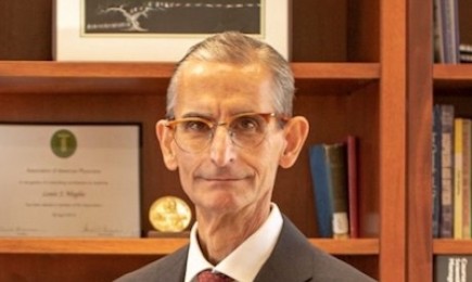 A photo of a person in a gray suit and red tie.