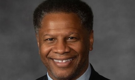 A photo of a person in a black jacket and red bow tie.