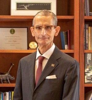 A photo of a person in a gray suit and red tie.