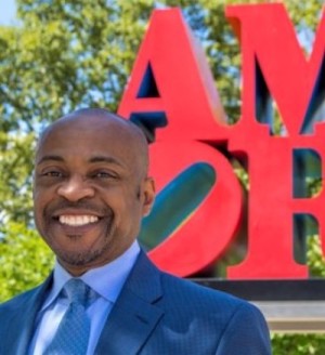 A photo of a person in front of a red sign.
