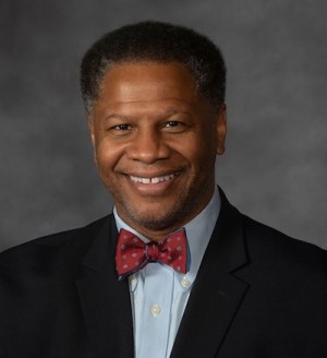 A photo of a person in a black jacket and red bow tie.